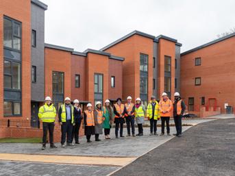 A group of people in hi-vis jackets in front of new-build homes